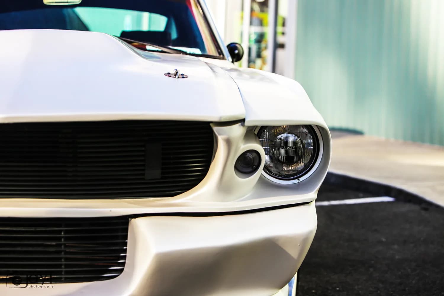 Front end of a satin white wrapped Ford Mustang Fastback, showing the film finish across the nose and headlights