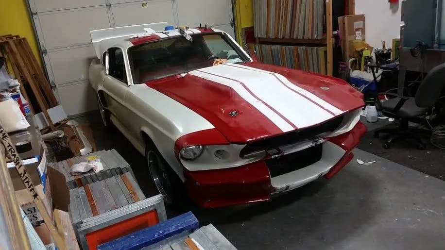 Ford Mustang with red and white racing stripes inside the Oly Wraps shop