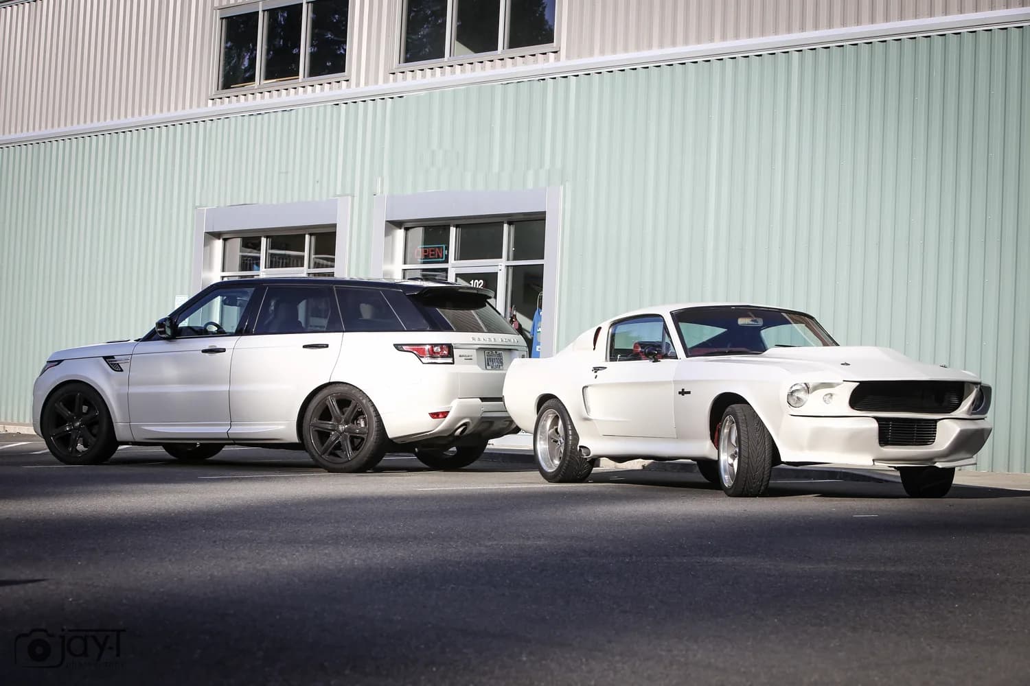 Range Rover Sport and a Ford Mustang Fastback, both wrapped in satin pearl white, parked outside the shop